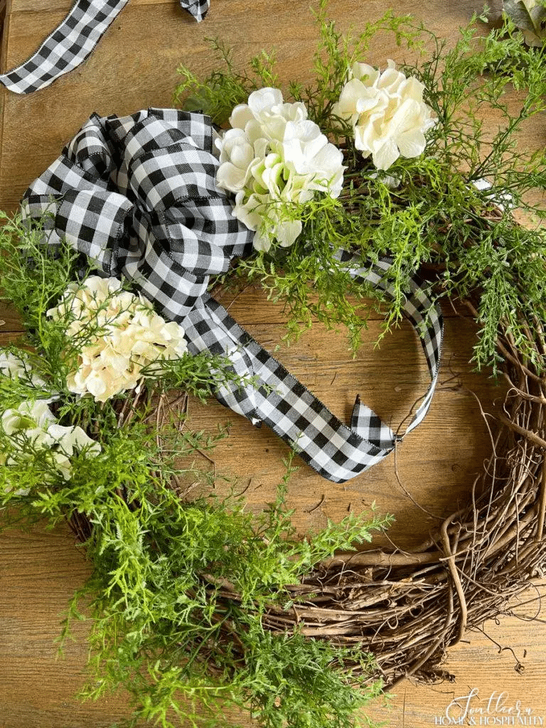 Inserting faux hydrangeas into grapevine wreath for summer