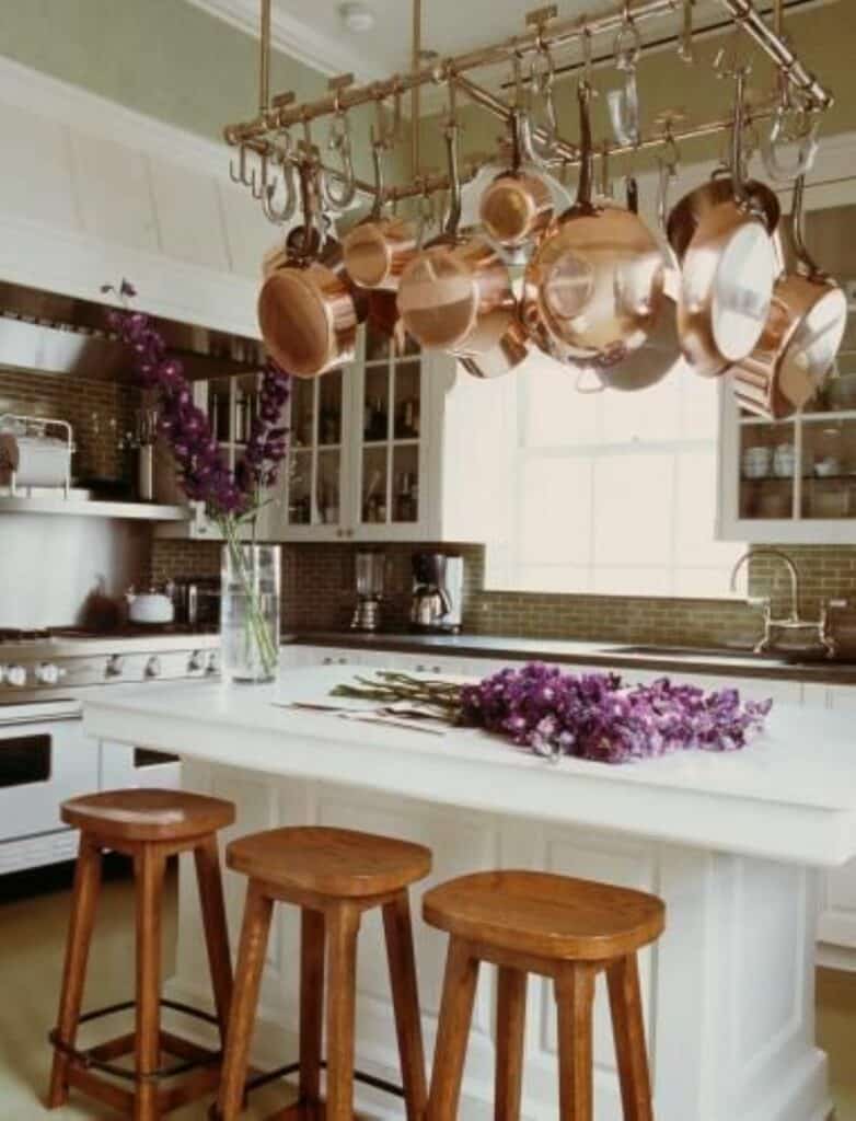 Copper pots and pans hanging from copper pot rack over kitchen island