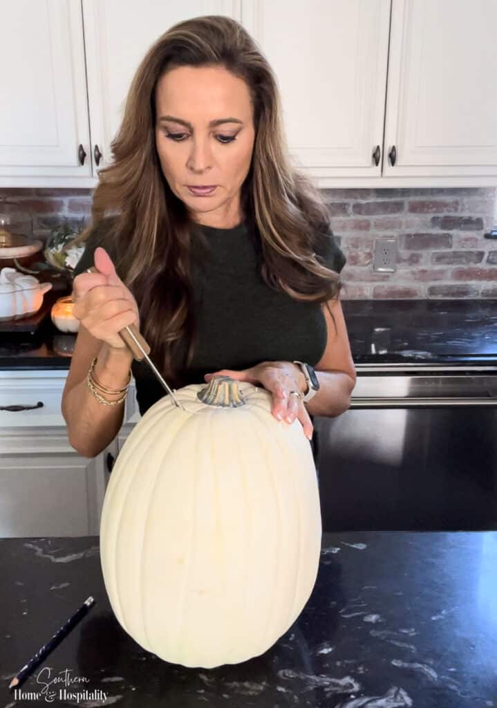 Cutting the top off of a faux foam pumpkin to make a vase