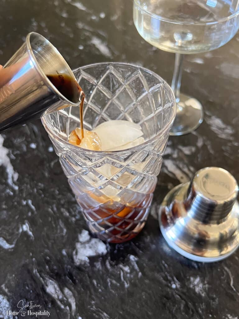 Pouring cold brew coffee concentrate into a cocktail shaker for espresso martini