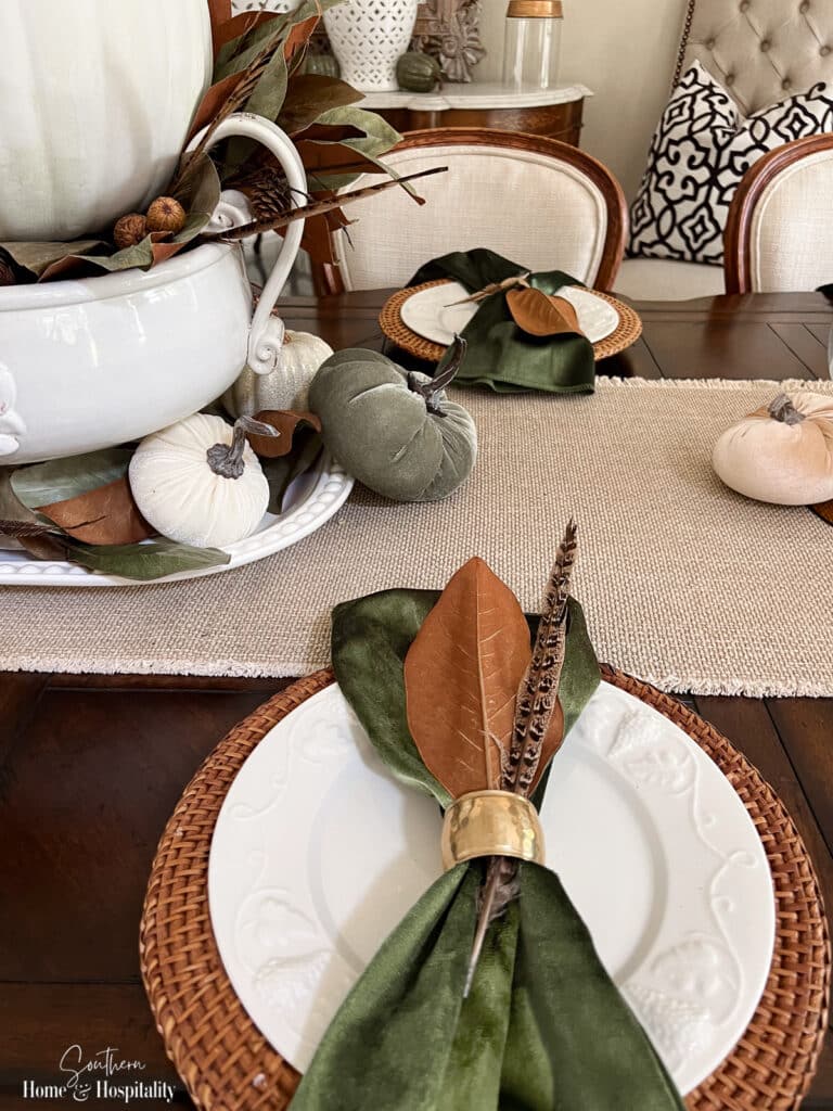 Green velvet napkins, magnolia leaf, and feather on fall place setting