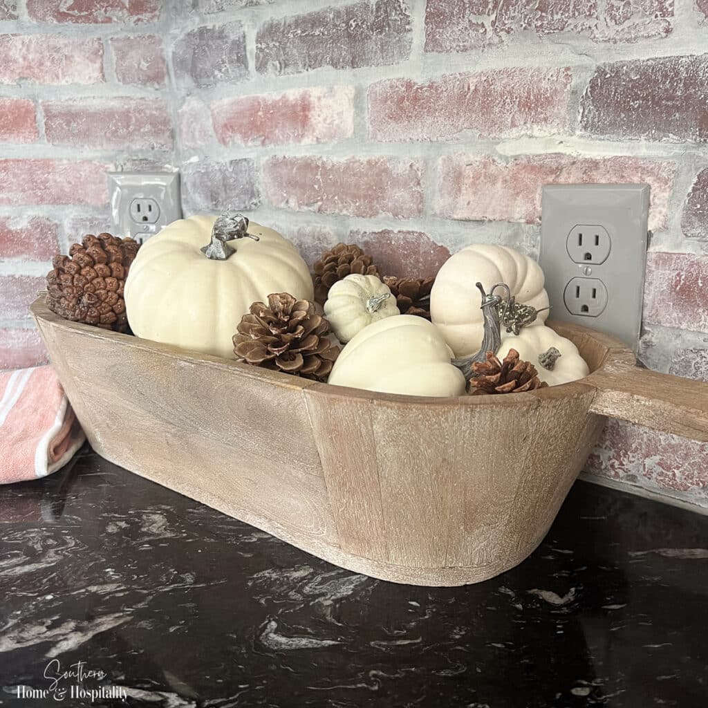 Fall dough bowl with white pumpkins and pinecones on kitchen counter