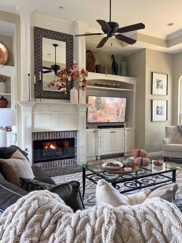 Family room fall decor with chunky throw, pumpkins, and fall leaves