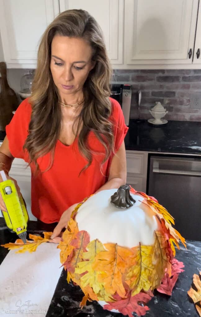 Covering a craft pumpkin in faux fall leaves