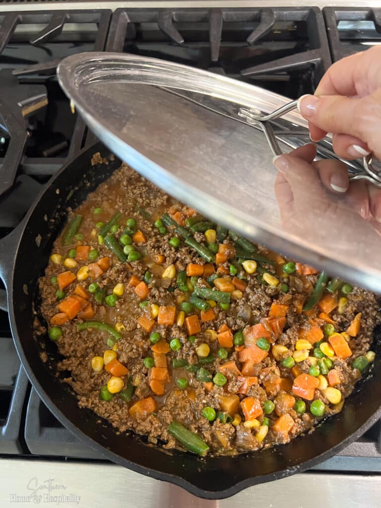 putting lid on shepherds pie meat and vegetables to cook on stovetop
