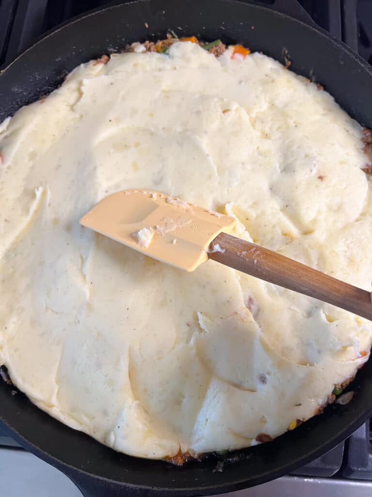 spreading mashed potatoes over meat layer of shepherd's pie