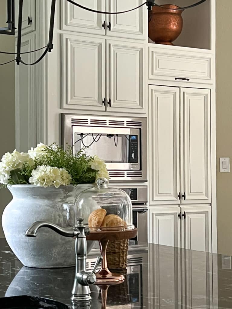 Large copper pot in kitchen alcove in white cabinets