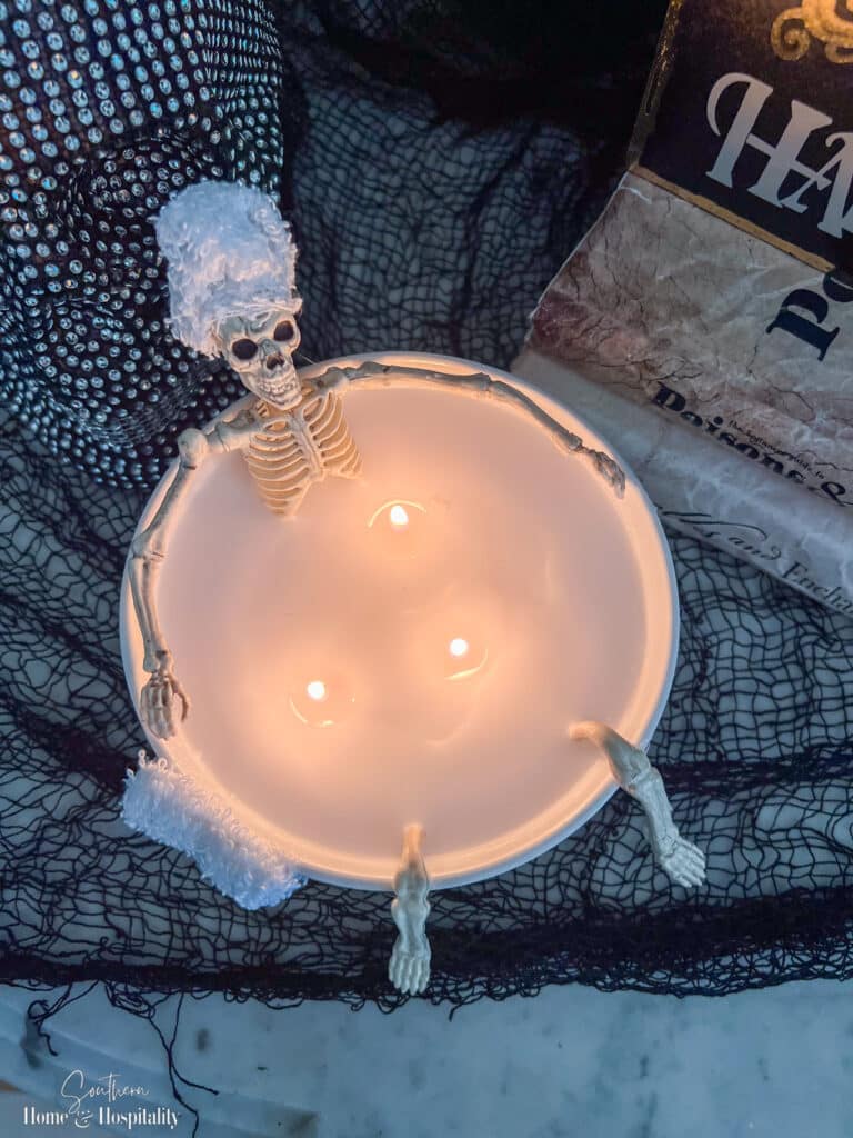 Skeleton candle soaking in tub with towel on head