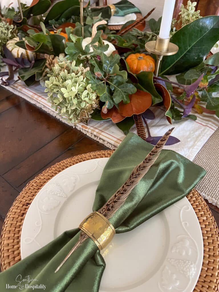 Green velvet napkin with brass napkin ring and pheasant feather