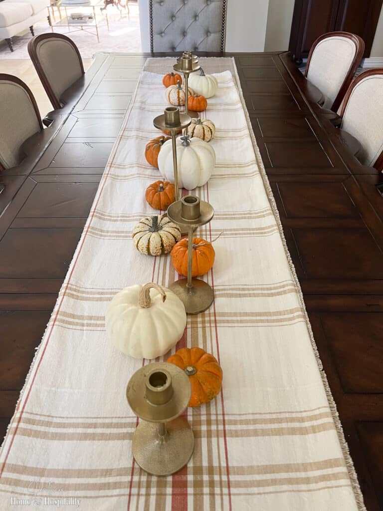 Orange and white pumpkins lining center of dining table