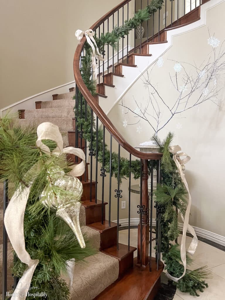 Plain green garlands on staircase with gold bows and ornaments