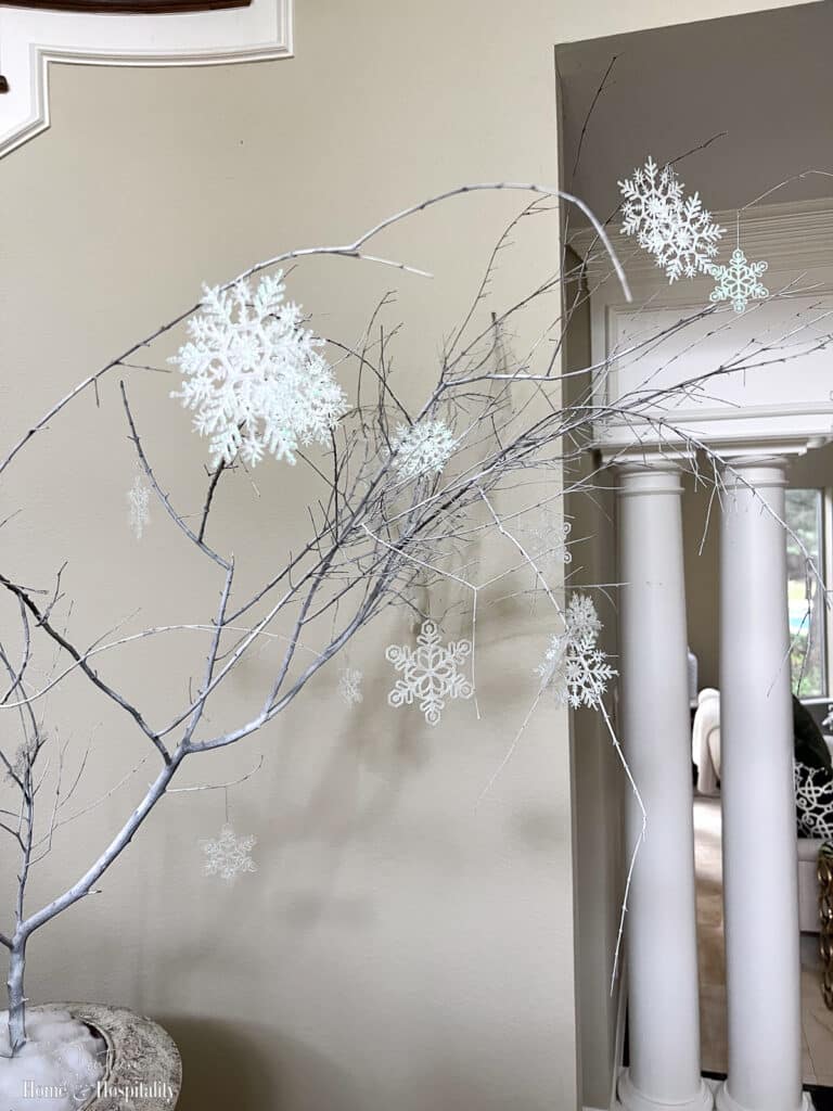 Snowflake ornaments on bare tree branch in urn