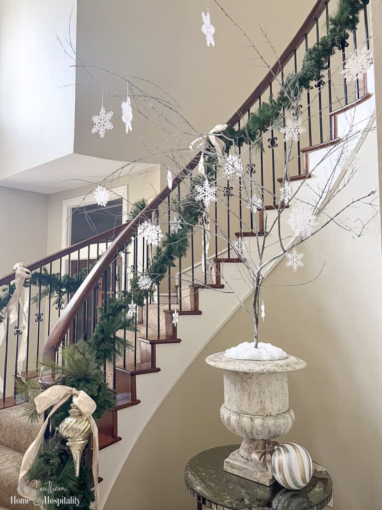 Snowflake ornaments hanging on tree branch in foyer urn