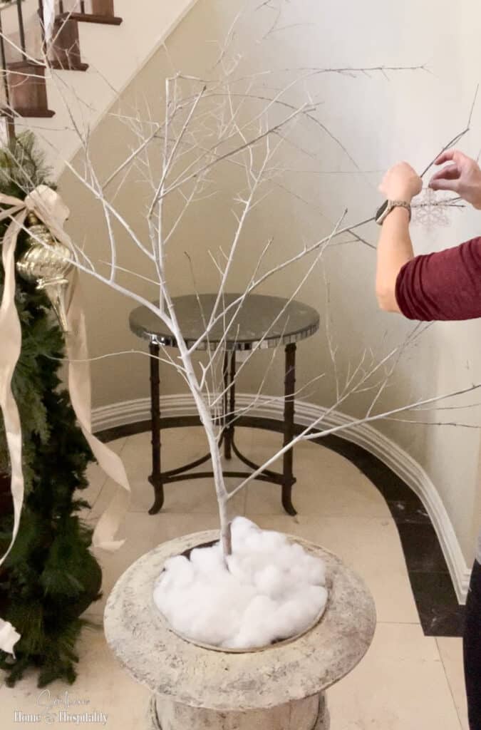 Hanging snowflake ornaments on foraged tree branch in planter