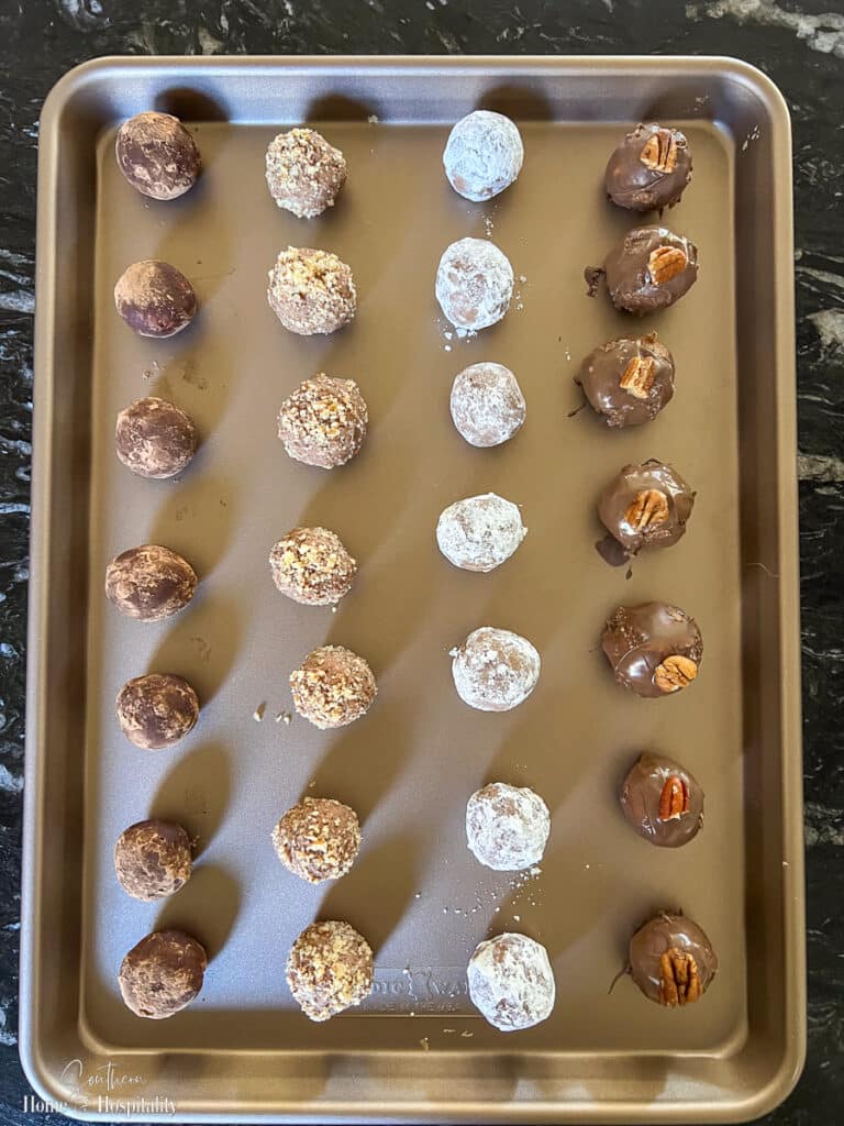 Assorted bourbon balls with cocoa powder, nuts, confectioners sugar, and melted chocolate