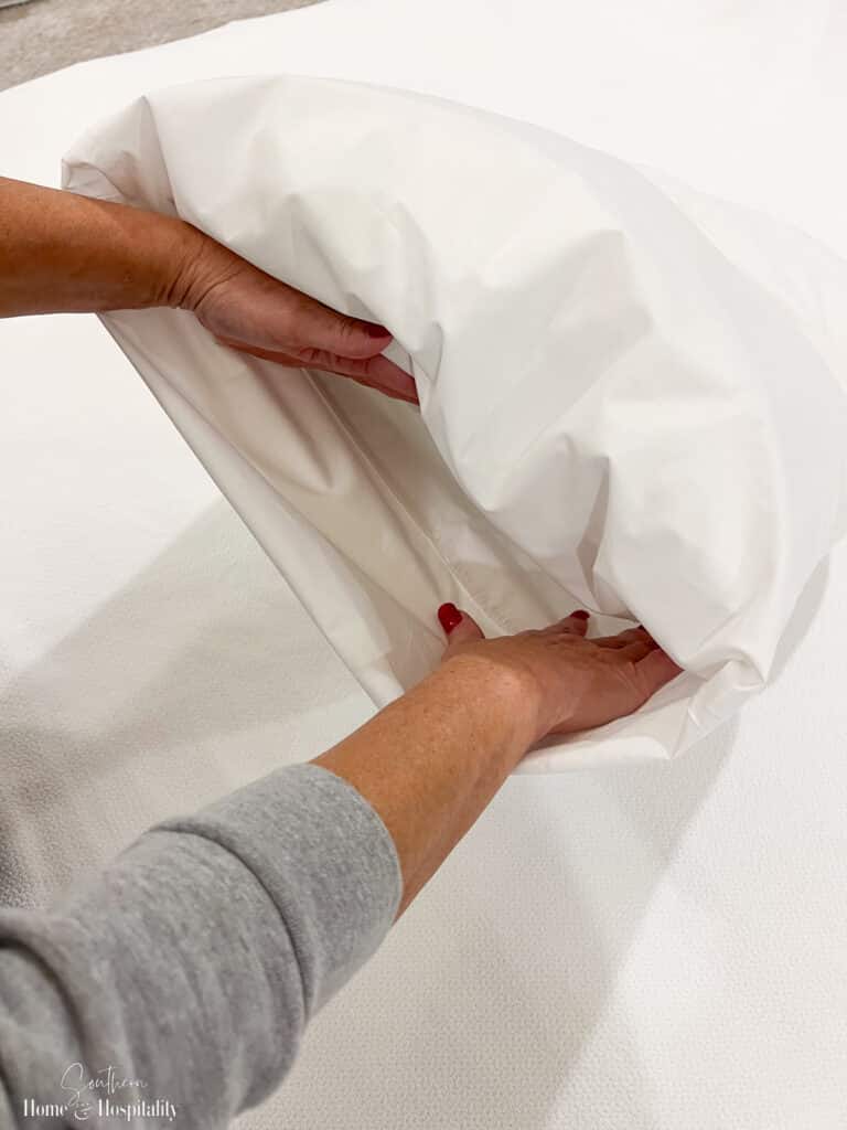 Tucking the ends of a pillowcase in to cover the bed pillow
