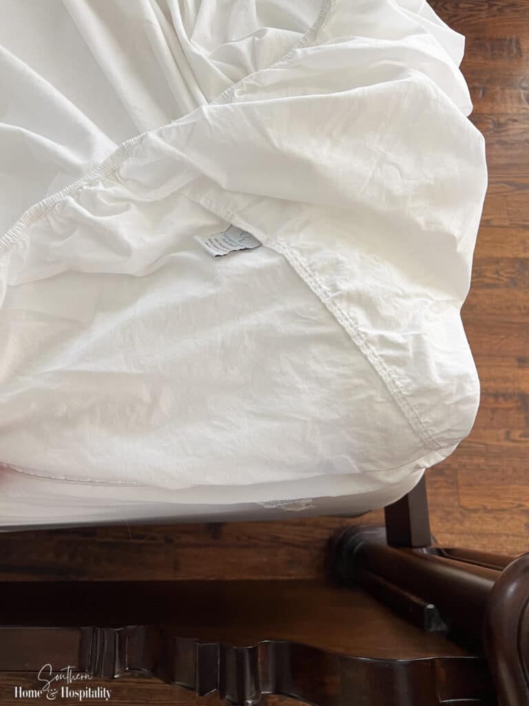 Tag of fitted sheet lined up with corner point of mattress