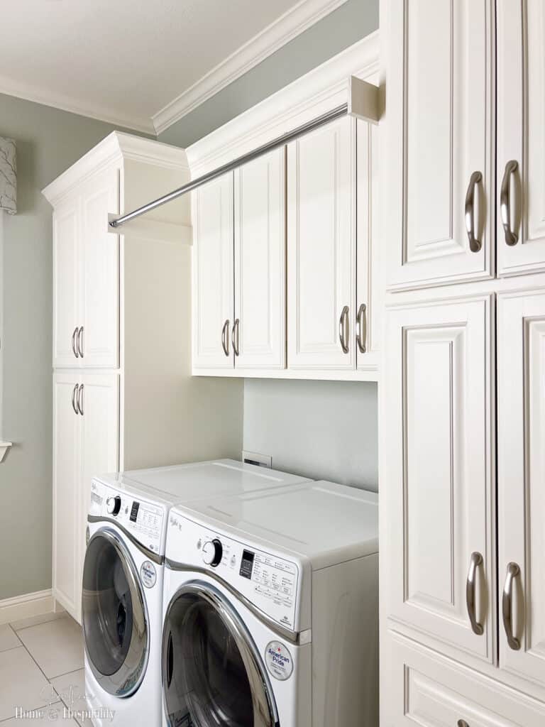 Clothes rod mounted over washer and dryer between cabinets