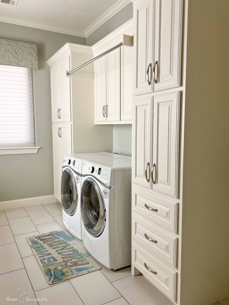 Laundry room with cabinets and hanging clothes rod over washer and dryer