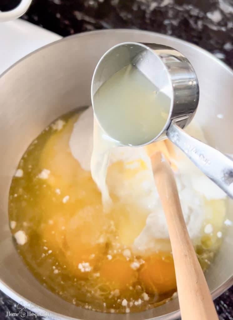 Pouring lemon bundt cake ingredients in mixing bowl