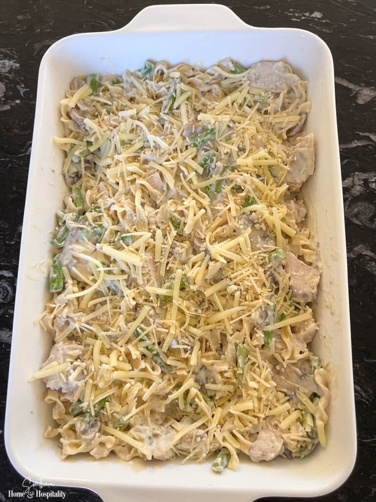 Unbaked asparagus and chicken casserole topped with shredded cheddar and parmesan