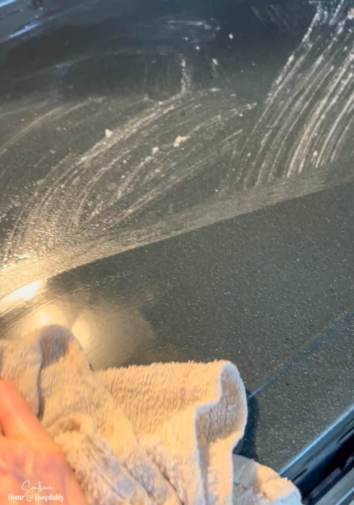 Wiping away baking soda paste from oven