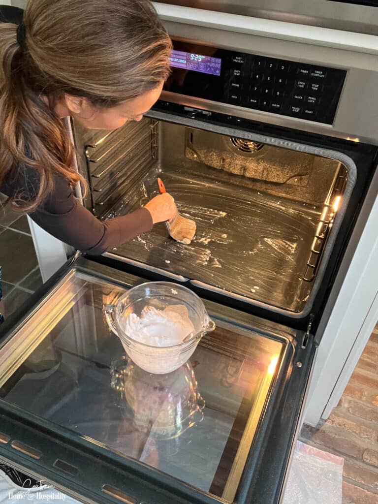 Applying baking soda paste to oven interior