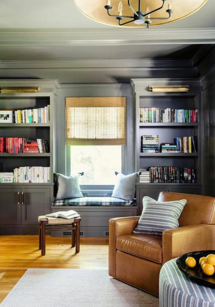 Cozy leather chair in front of bookcases flanking a window seat