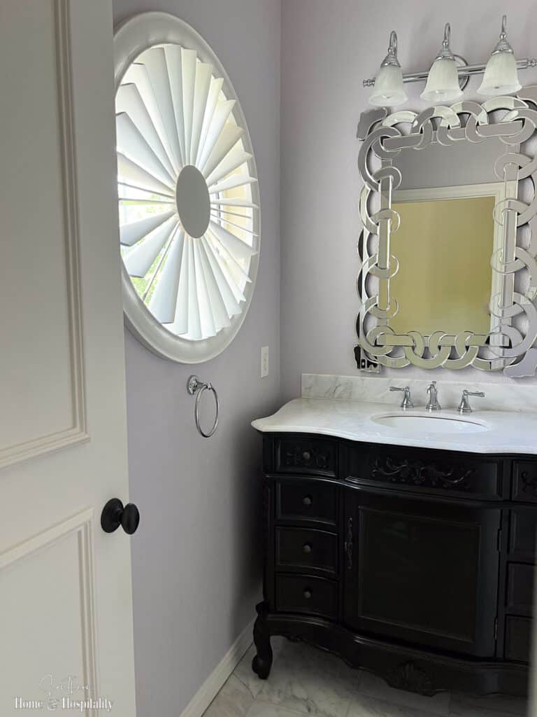 Round window with plantation shutters in bathroom
