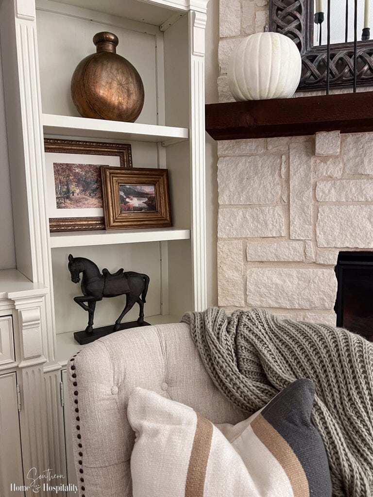 Updated entertainment center painted to match the trim with wallpaper, gold hardware, picture lights, and styled shelves.