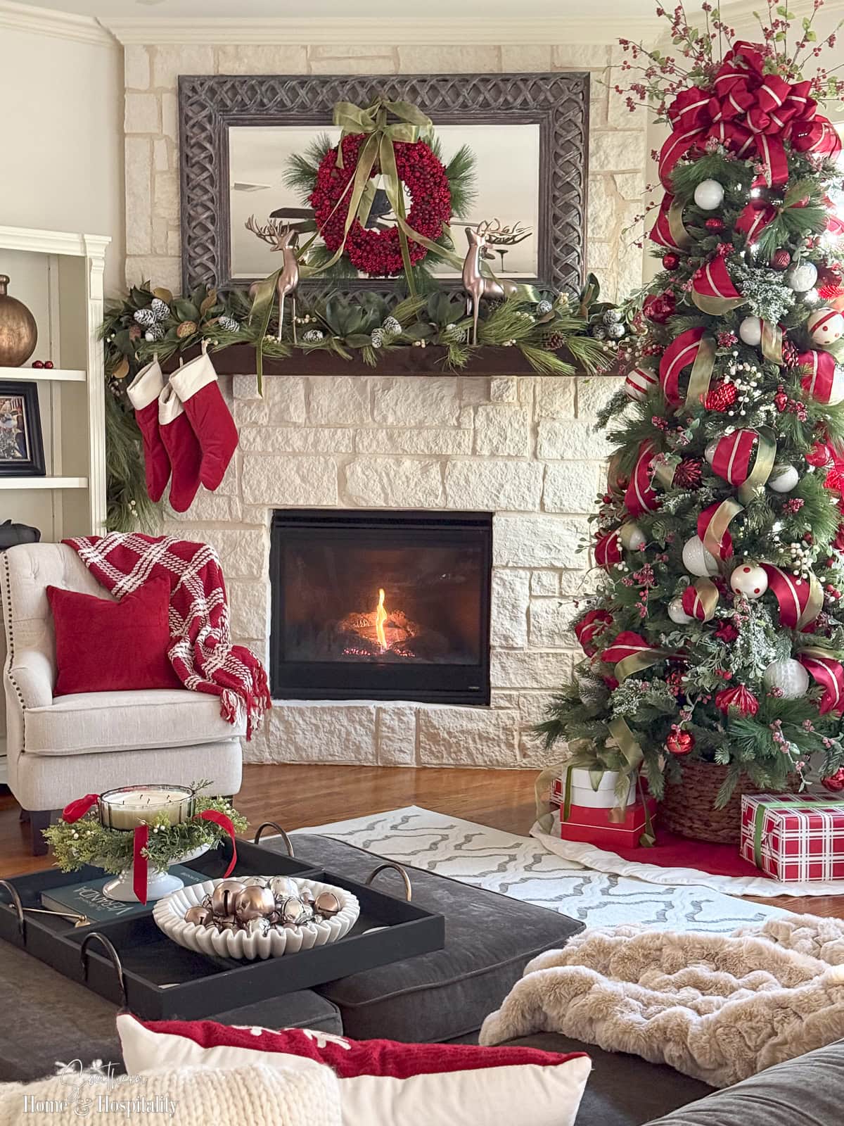 Decorated Christmas tree with ribbon loops, ornaments, and tree topper bow in living room next to fireplace
