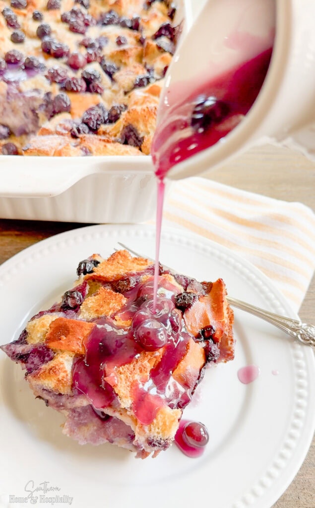 Pouring blueberry sauce over french toast casserole