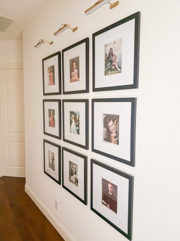 Symmetrical gallery wall with black frames and picture lights