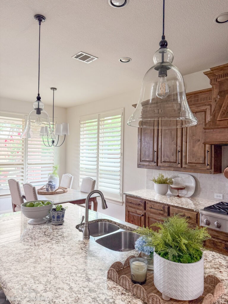 Updated glass bell kitchen pendant lights replacing outdated pendants over brown granite island