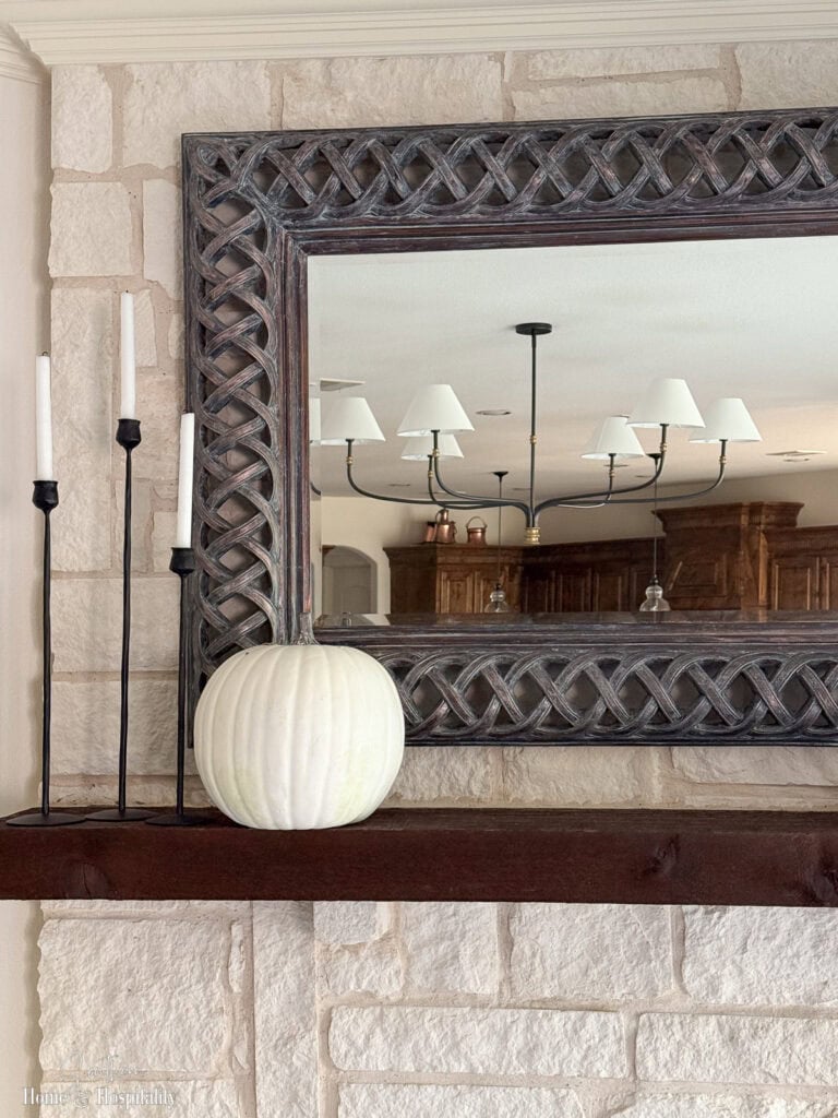 Tall black iron candlesticks and a white pumpkin on a fall mantel.
