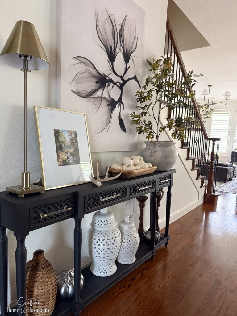 Entryway decorated for fall with subdued green branches and neutral accents.