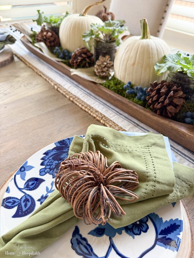 Fall tablescape place setting with layered napkins in soft blue and green.
