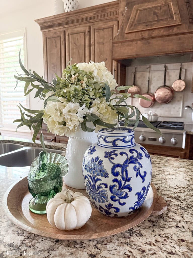 Rustic tray with chinoiserie jar, vintage green glass bowl, and hydrangeas.