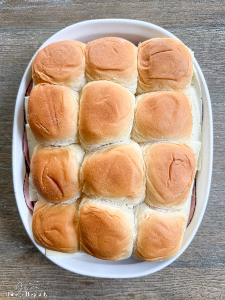 Ham and cheese sliders assembled in baking dish with top rolls added.