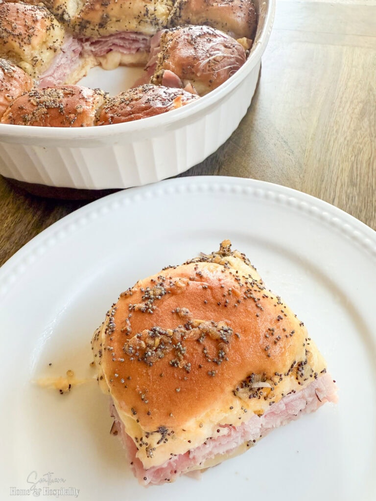Ham and cheese slider with melted Swiss and golden poppyseed glaze served on a white plate.