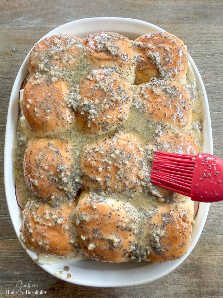 Buttery poppyseed glaze brushed over tops of ham and Swiss sliders before baking.