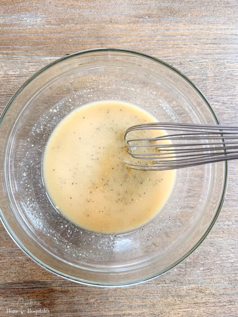 Butter mixture with Dijon, Worcestershire, onion, and poppy seeds being whisked for ham and cheese sliders with poppyseed glaze.