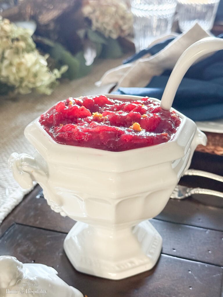 Fresh cranberry sauce with orange zest garnish in a white serving tureen — the perfect make-ahead holiday side.