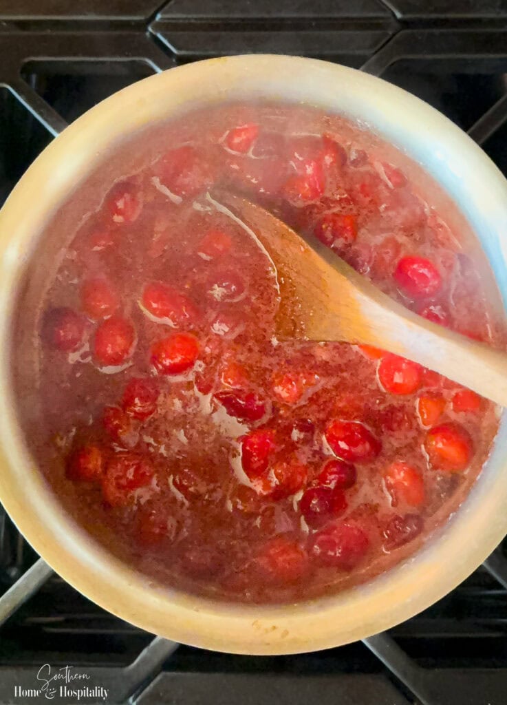 Cranberries simmering on the stove and beginning to pop as the sauce thickens.