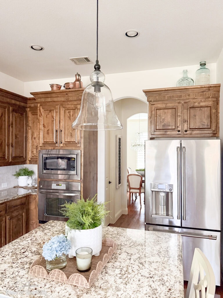 Kitchen with upper cabinets that stop short of ceiling and minimal decor above— copper, and glass groupings spaced apart for balanced look