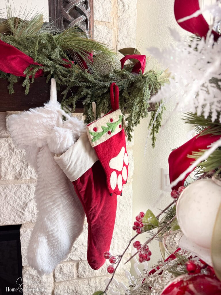 Red velvet and white faux fur stockings hanging from mantel, including one for dog.