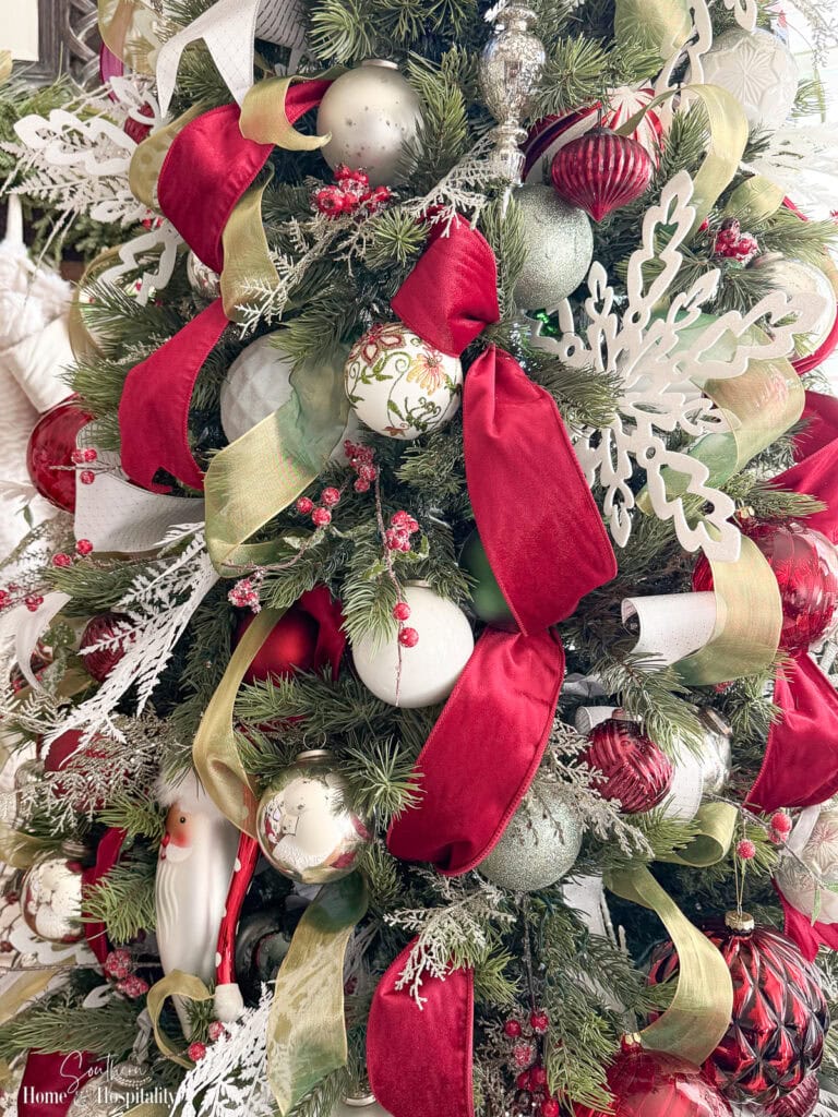 Close-up of Christmas ornaments hanging on a decorated tree before being carefully removed.