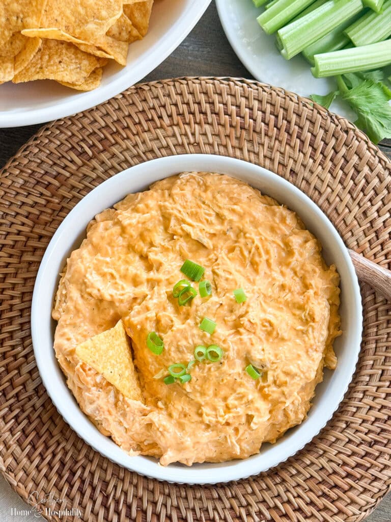 Overhead view of buffalo chicken dip garnished with green onions in a white bowl