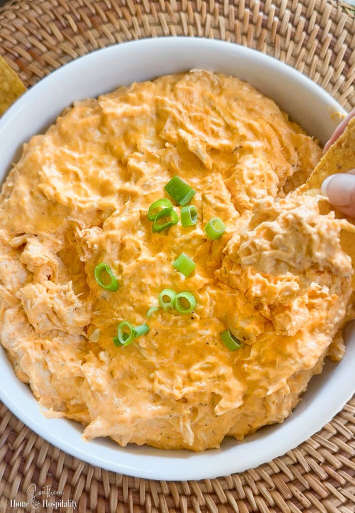 Tortilla chip dipped into creamy buffalo chicken dip served warm