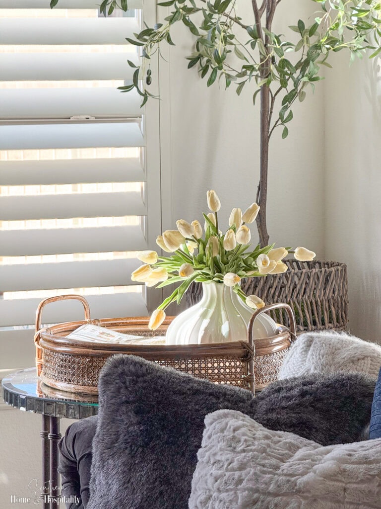 Corner of a softly painted neutral living room with natural light, woven textures, and light-colored walls to enhance openness.
